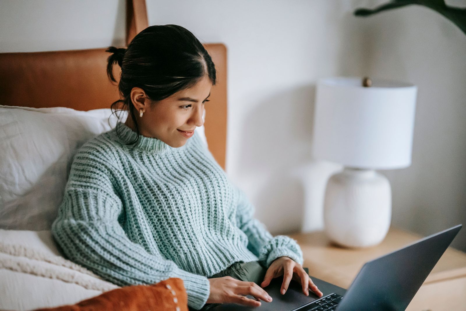 Someone relaxing in bed, sending a SaphraONE payment from their laptop